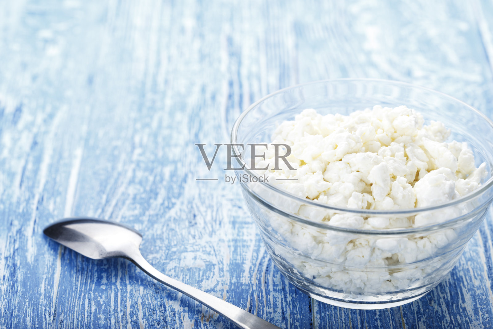 白软干酪装在盘子里，勺子放在桌上。照片摄影图片