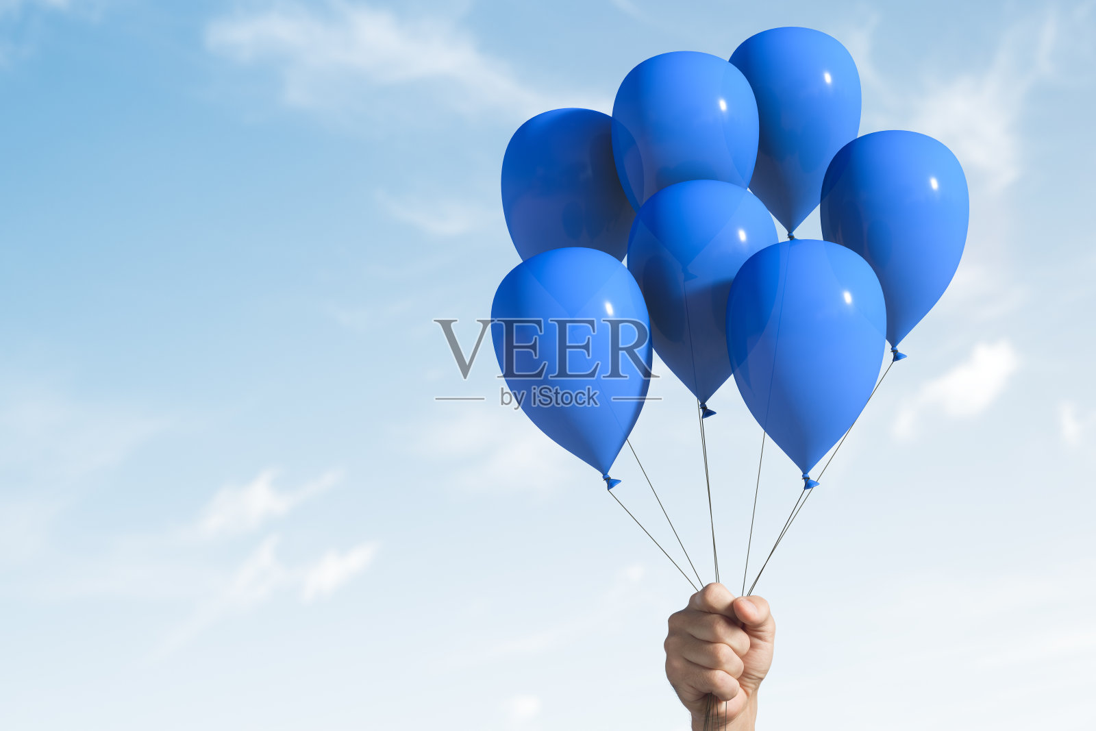 举着几个蓝色的气球。照片摄影图片