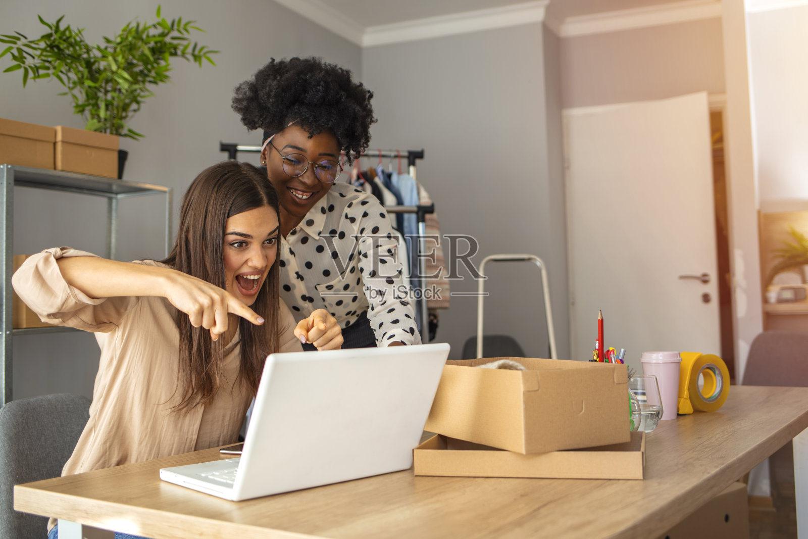 两个愉快的年轻人用电脑庆祝他们的成功照片摄影图片