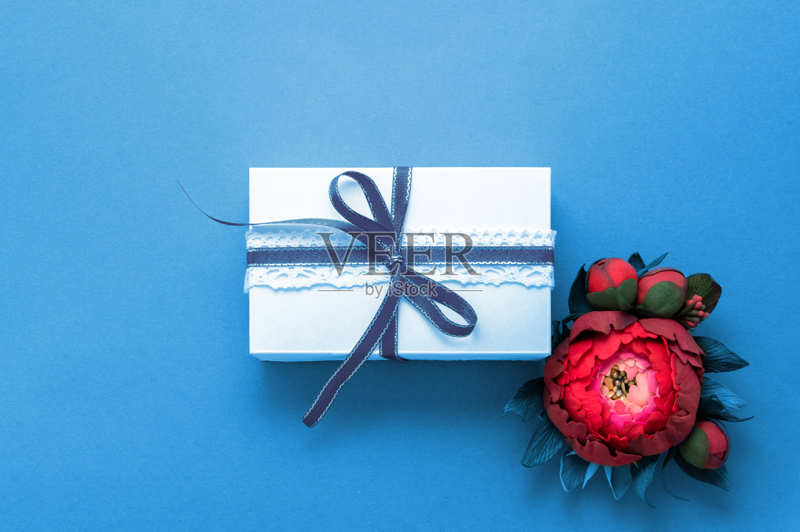 礼盒礼品装饰平铺。白色礼物丝带粉红色花朵俯视图。祝贺模板横幅蓝纸照片摄影图片