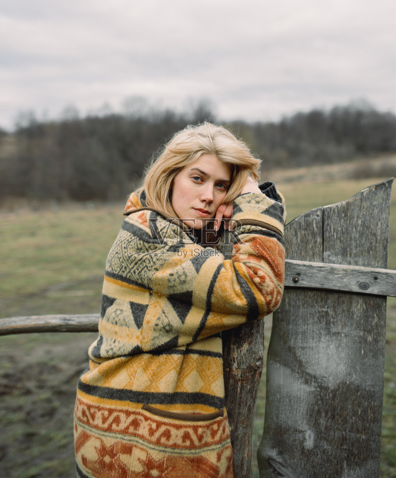 年轻漂亮的女人靠在篱笆上照片摄影图片