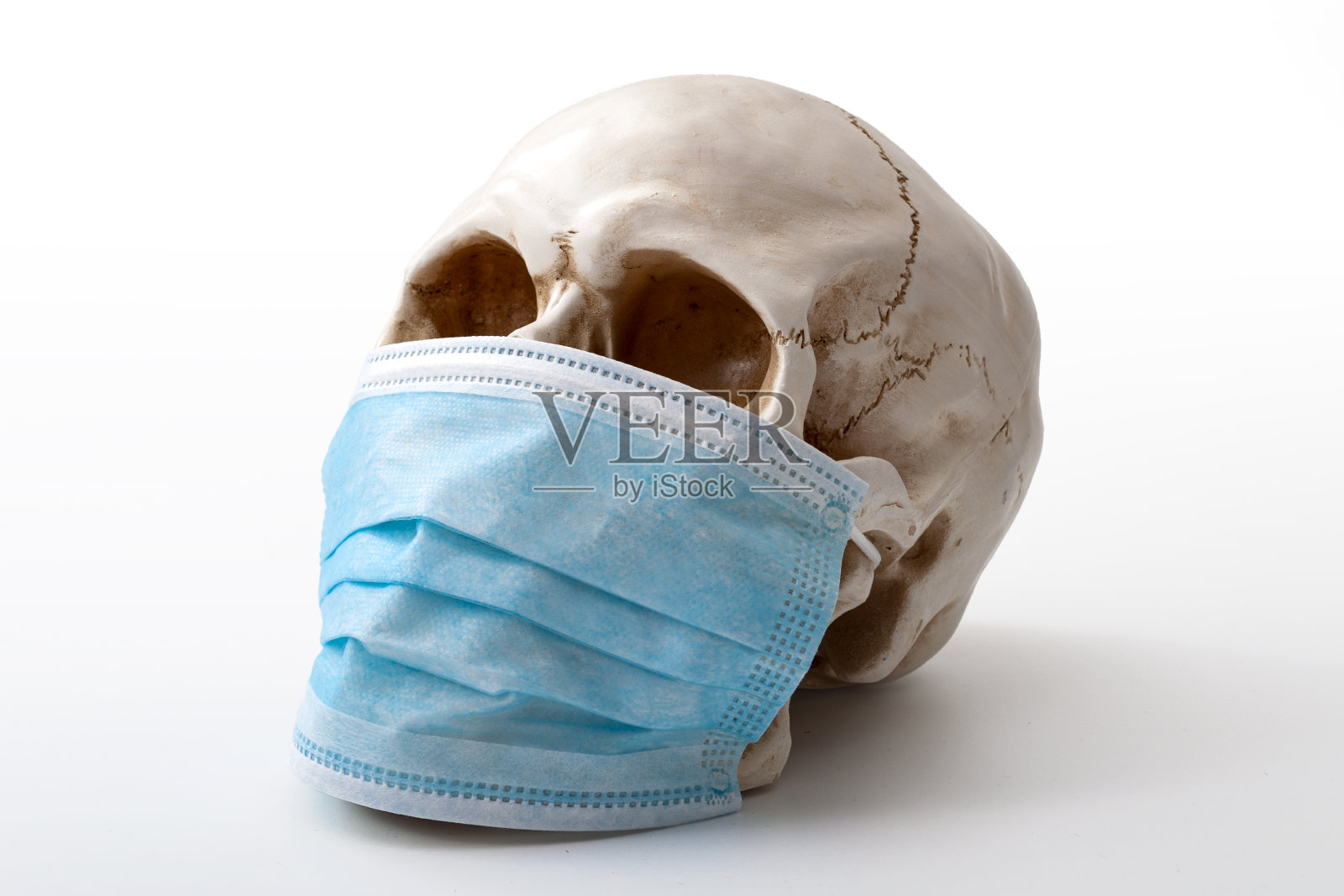 传播大流行恐慌，传染性流感流行和传染性疾病概念，戴着蓝色外科口罩的颅骨隔离在白色背景和剪切路径切断照片摄影图片