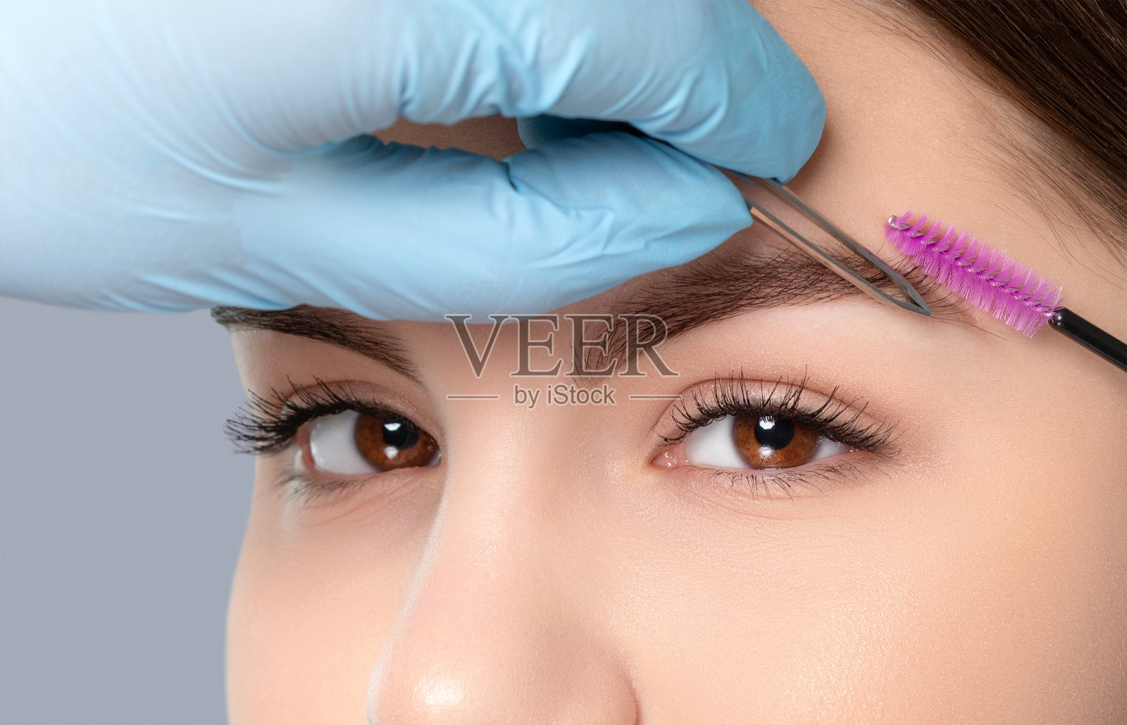 化妆师先用镊子拔眉毛，然后再用指甲花染色。美容院的女性美容。照片摄影图片