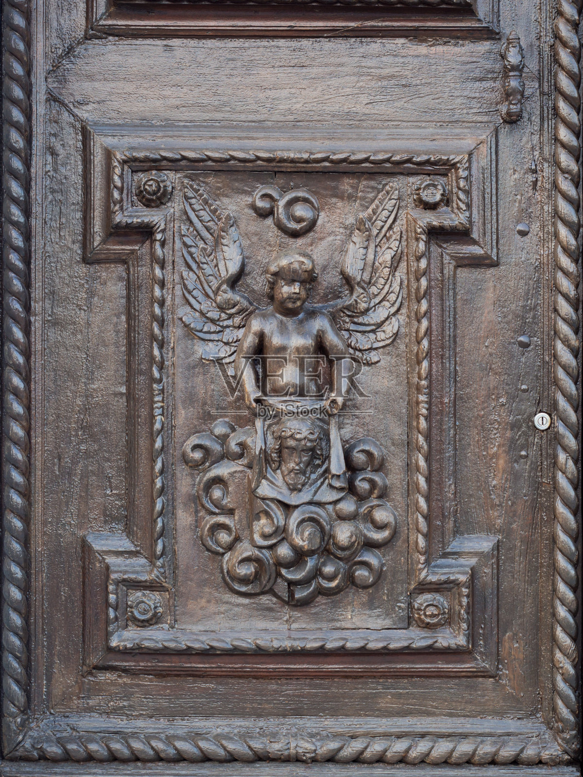 天使雕刻在一个古老的意大利教堂的木制门上。照片摄影图片