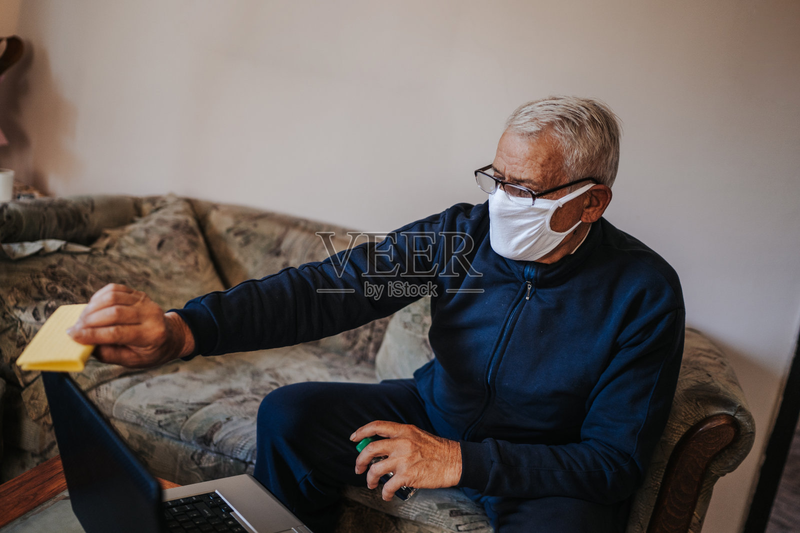 老家伙给他的笔记本消毒照片摄影图片