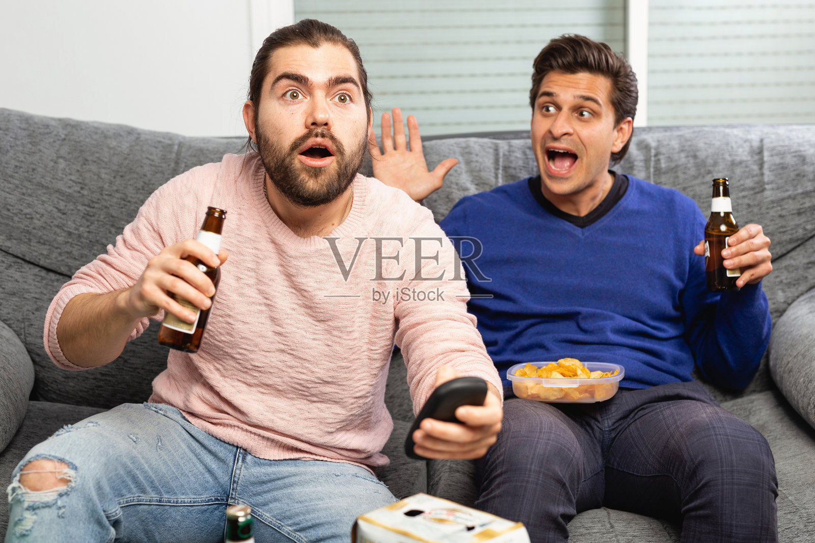 两个男人一边在家喝啤酒，一边在电视上看比赛，开心地大喊大叫照片摄影图片