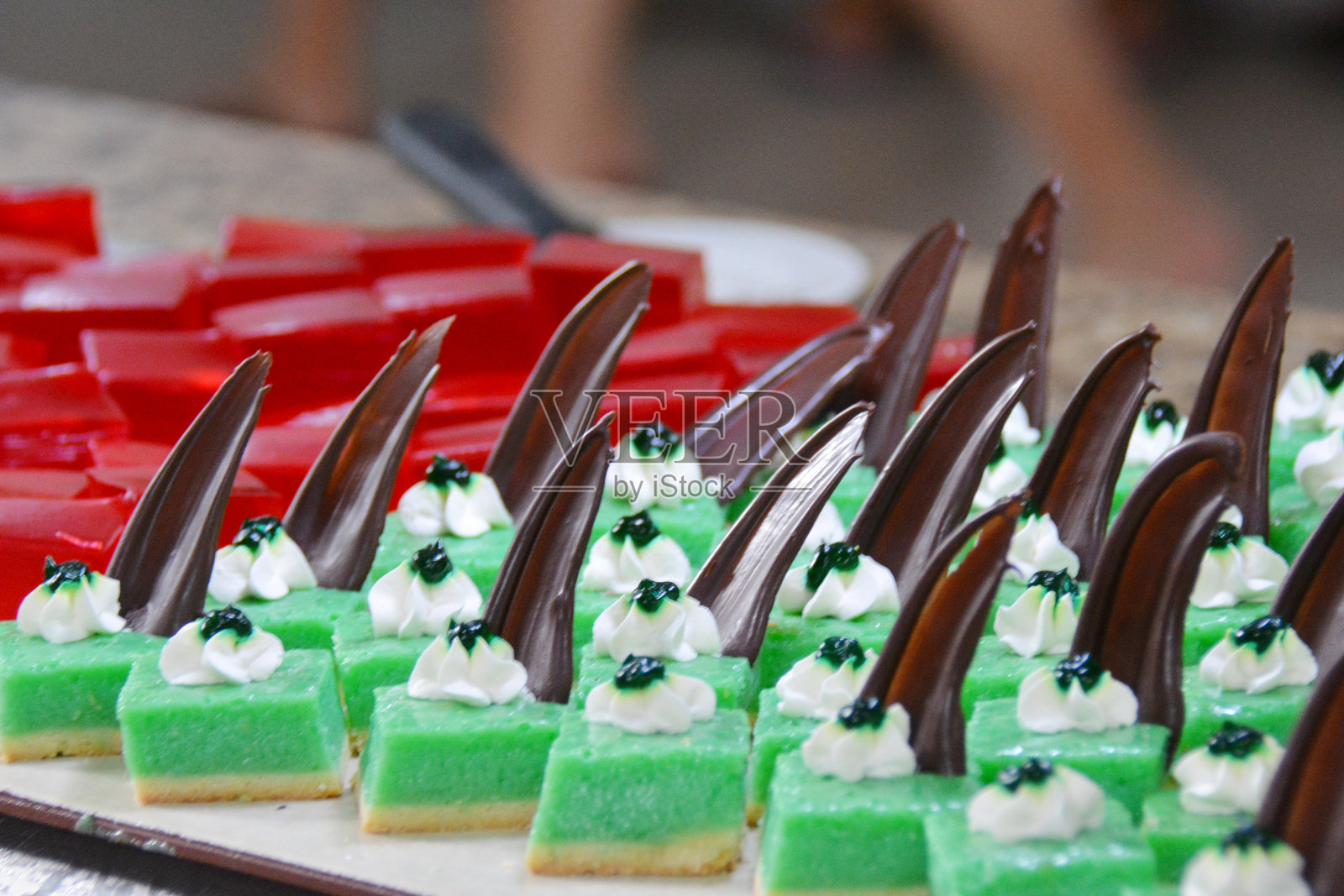在自助餐上切点甜点，绿色和粉色，用巧克力和奶油装饰照片摄影图片