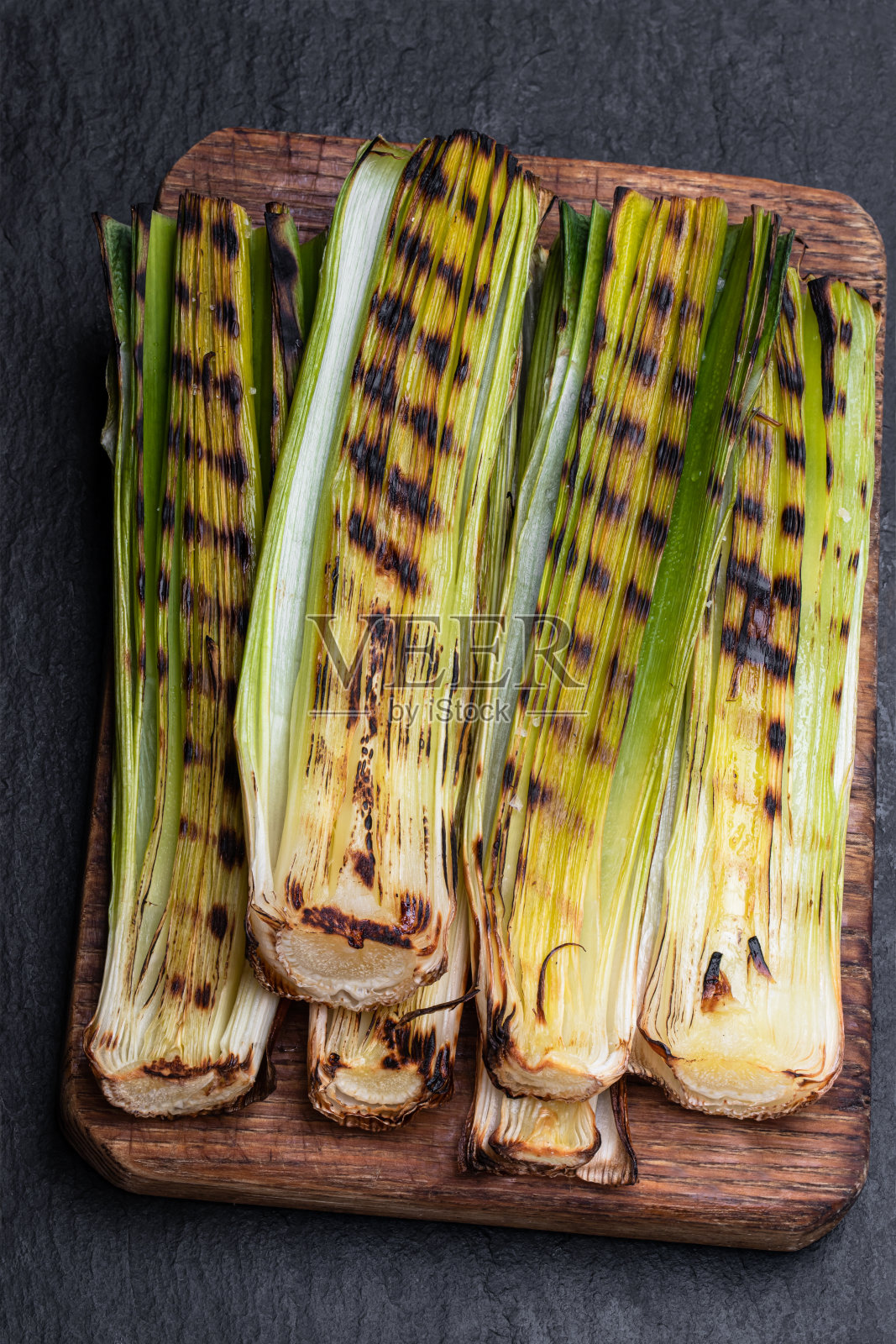 烤婴儿韭菜在黑色的石头背景照片摄影图片