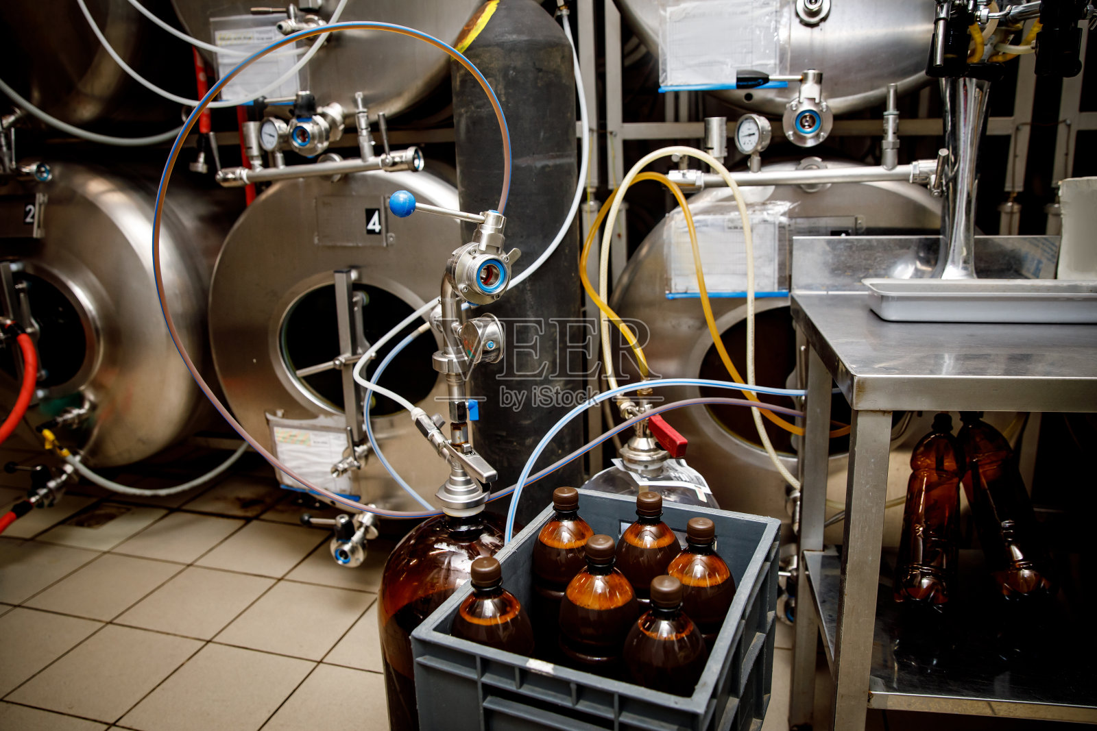 在酿造罐附近的塑料瓶里准备好的新鲜啤酒。照片摄影图片