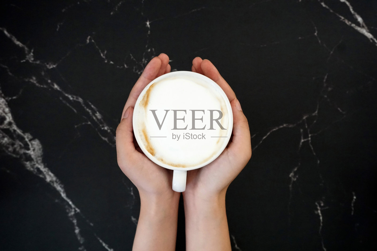 手捧一杯咖啡，以黑色大理石为背景照片摄影图片