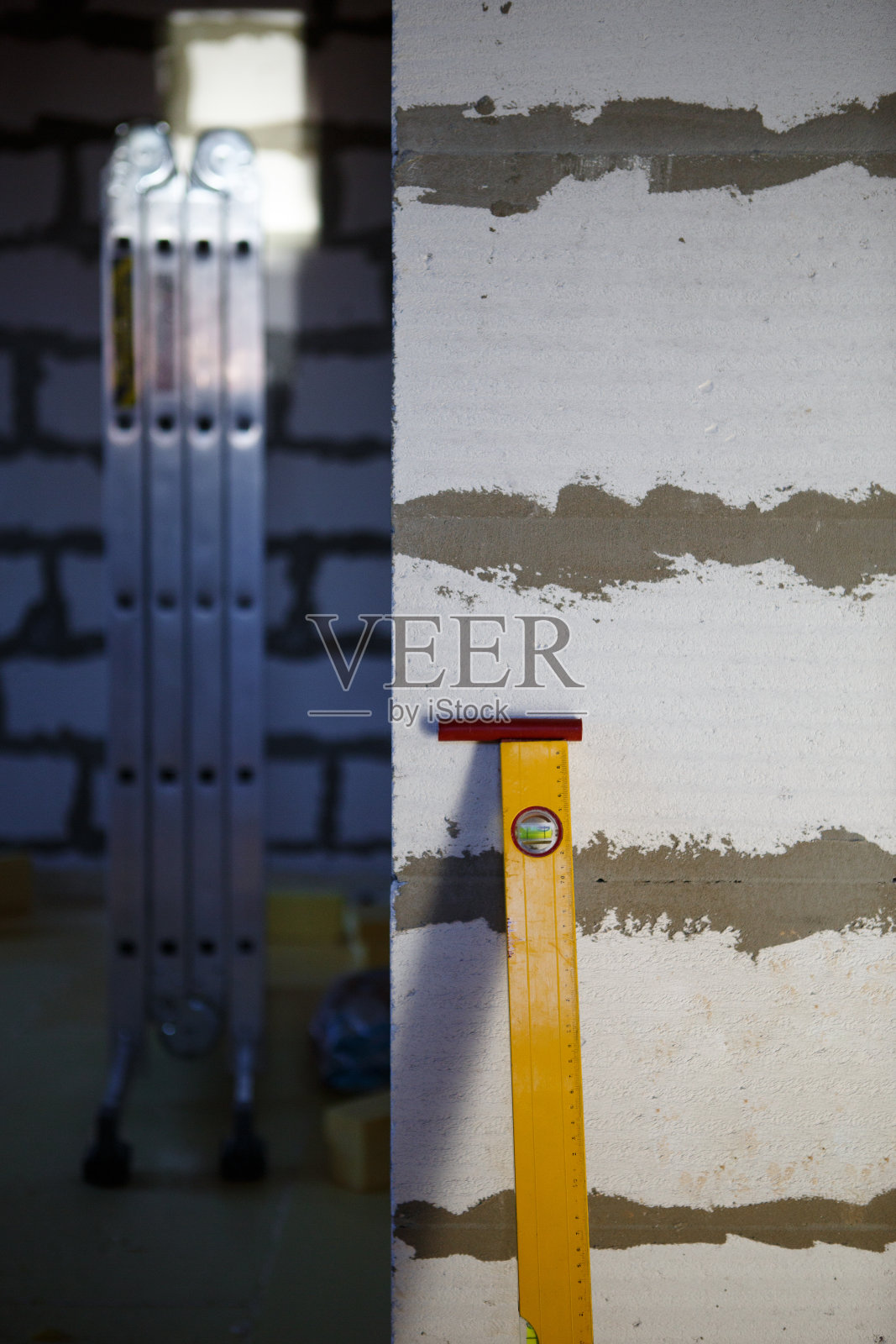 黄色建筑水平仪靠在由加气混凝土砌块建造的建筑墙壁上照片摄影图片