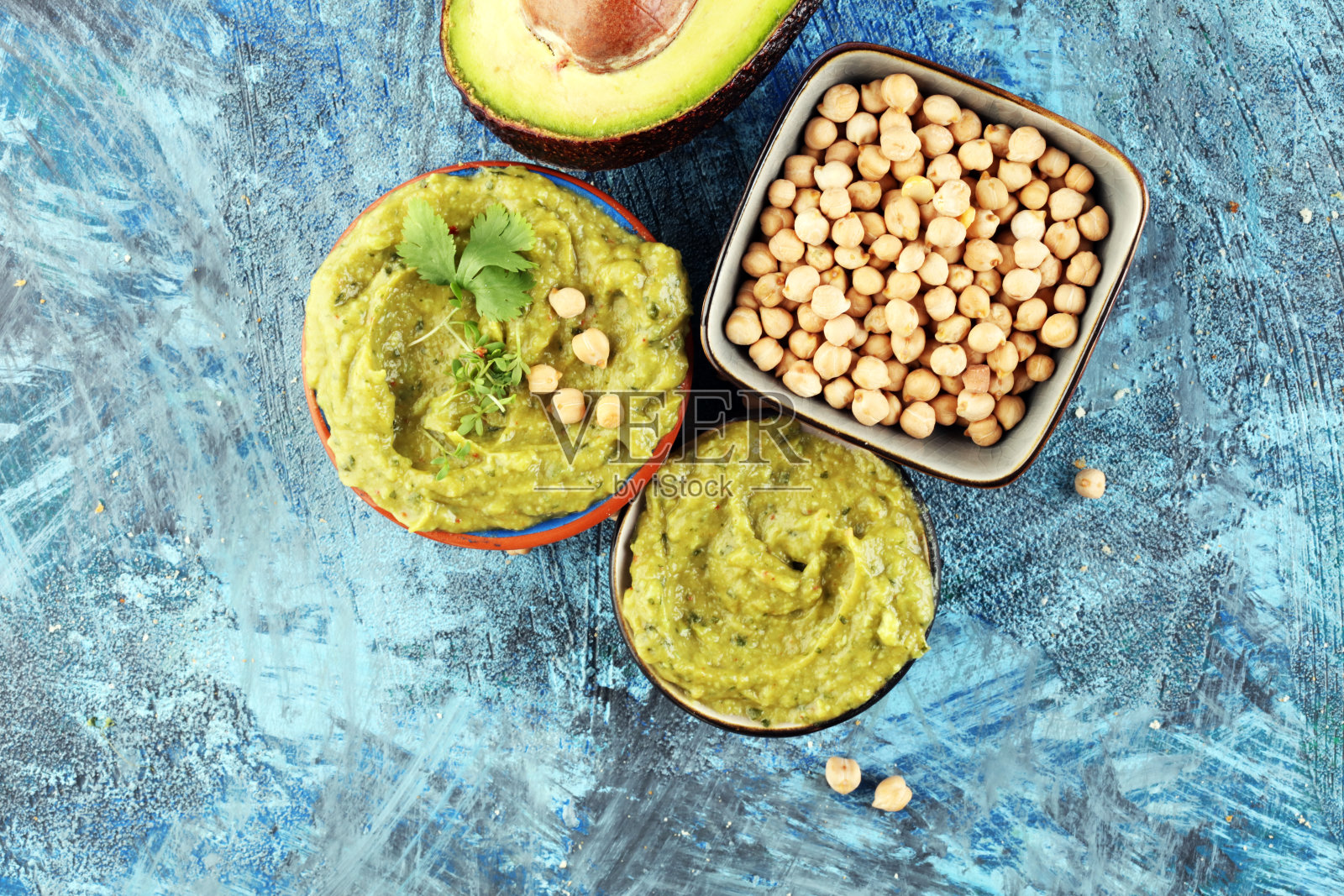 一碗绿色的鹰嘴豆泥，美味的鹰嘴豆和鳄梨奶油，背景是香草照片摄影图片