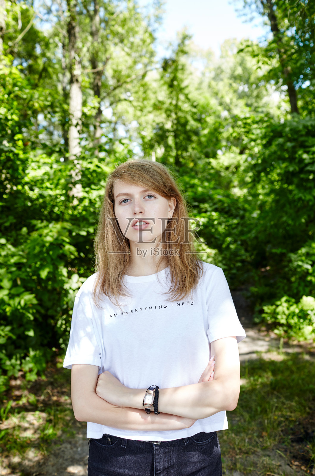 美丽迷人的女人在白色t恤摆姿势在夏季公园。活泼微笑的女孩在户外休息照片摄影图片