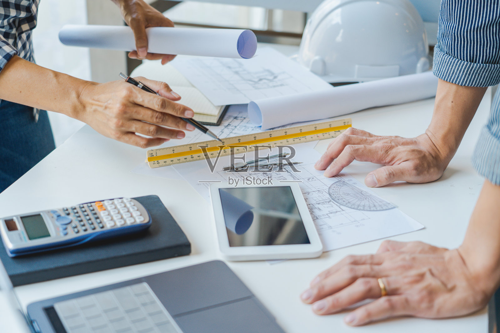 在一间现代化的办公室里，工程师在建筑设备的帮助下讨论楼层平面图和建筑设计图照片摄影图片