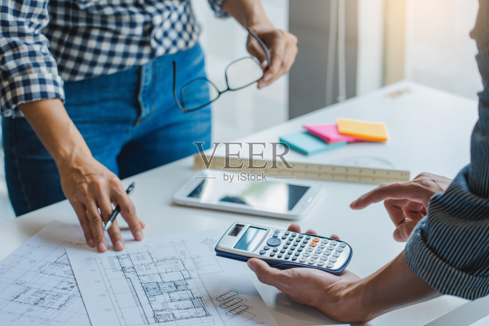 合作企业的设计师们正在办公室里对一个新的项目进行规划图纸的设计，在工地的办公桌旁照片摄影图片