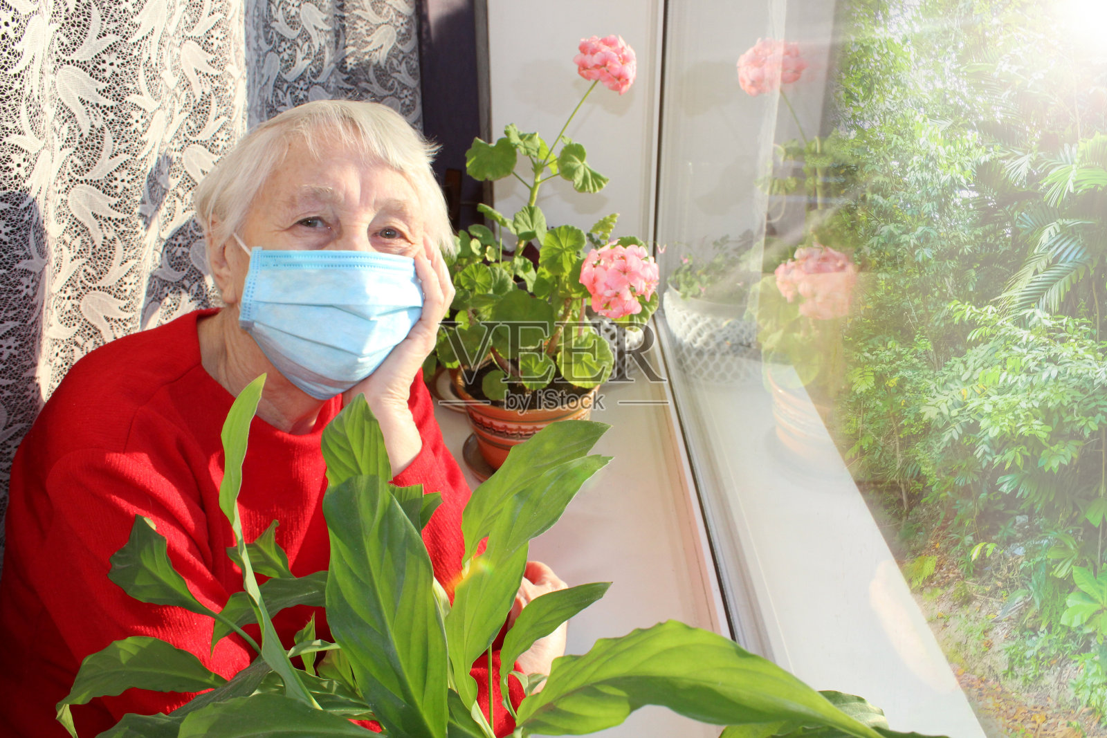 2019冠状病毒病、健康、安全和大流行概念——坐在窗边的孤独老年妇女照片摄影图片