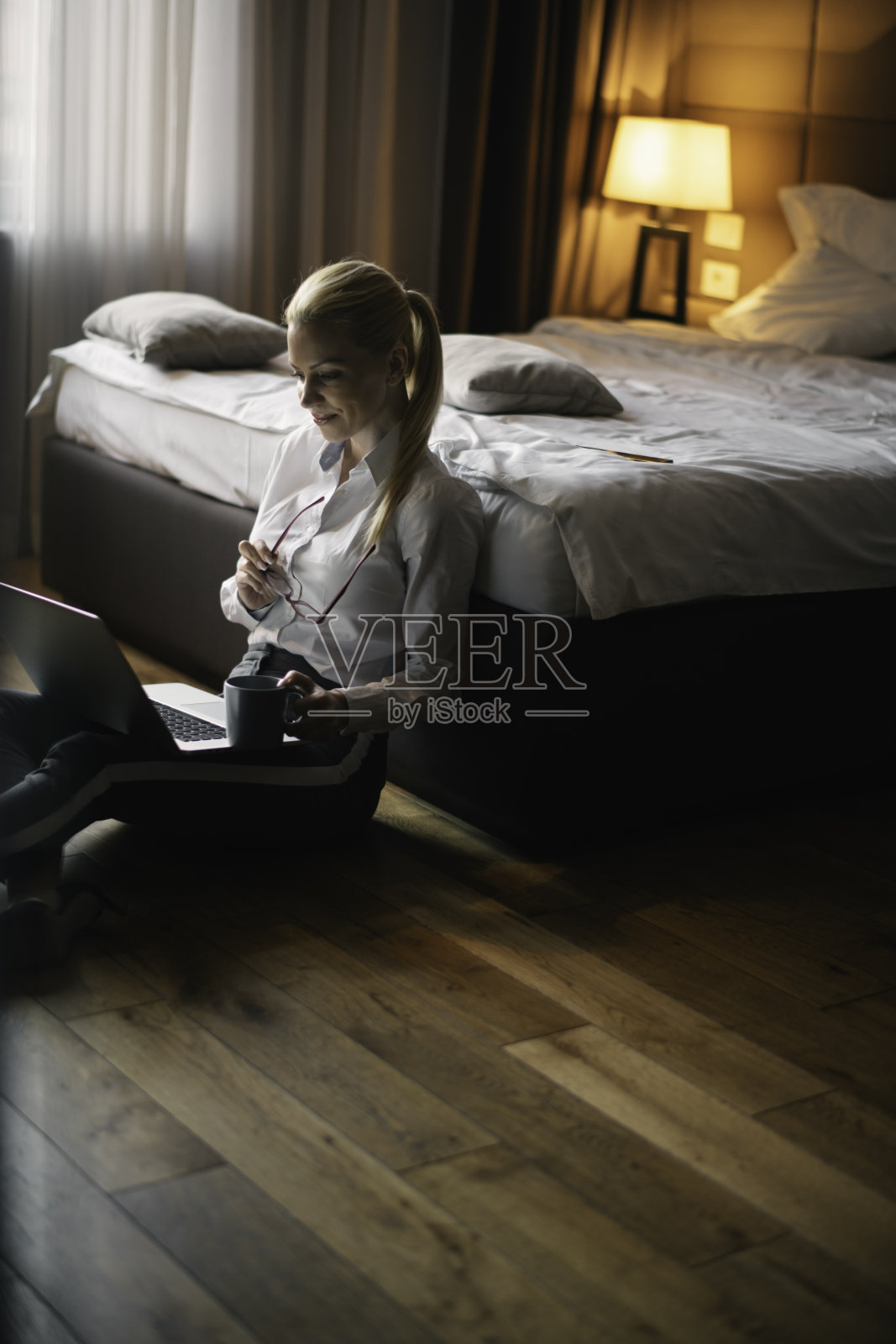 美丽的女商人在酒店房间的笔记本电脑上工作。照片摄影图片