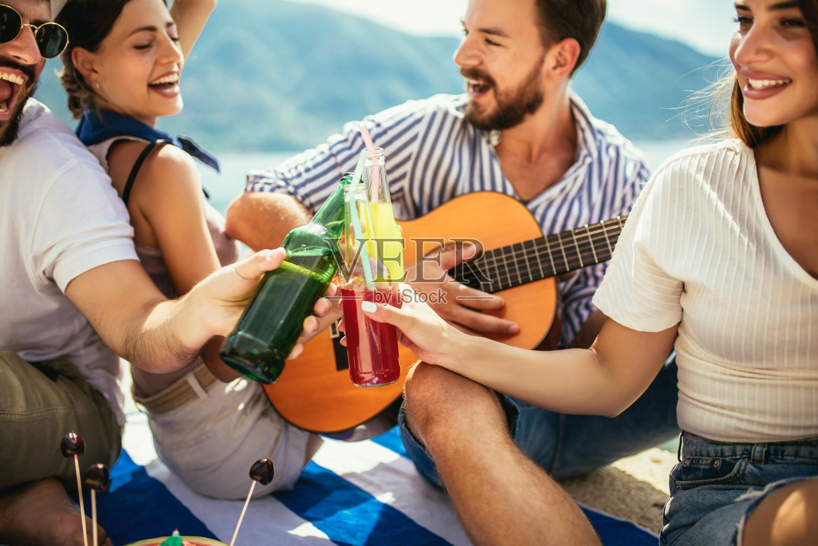 年轻人正在玩暑假。快乐的朋友们在海滩上喝着热带鸡尾酒。照片摄影图片