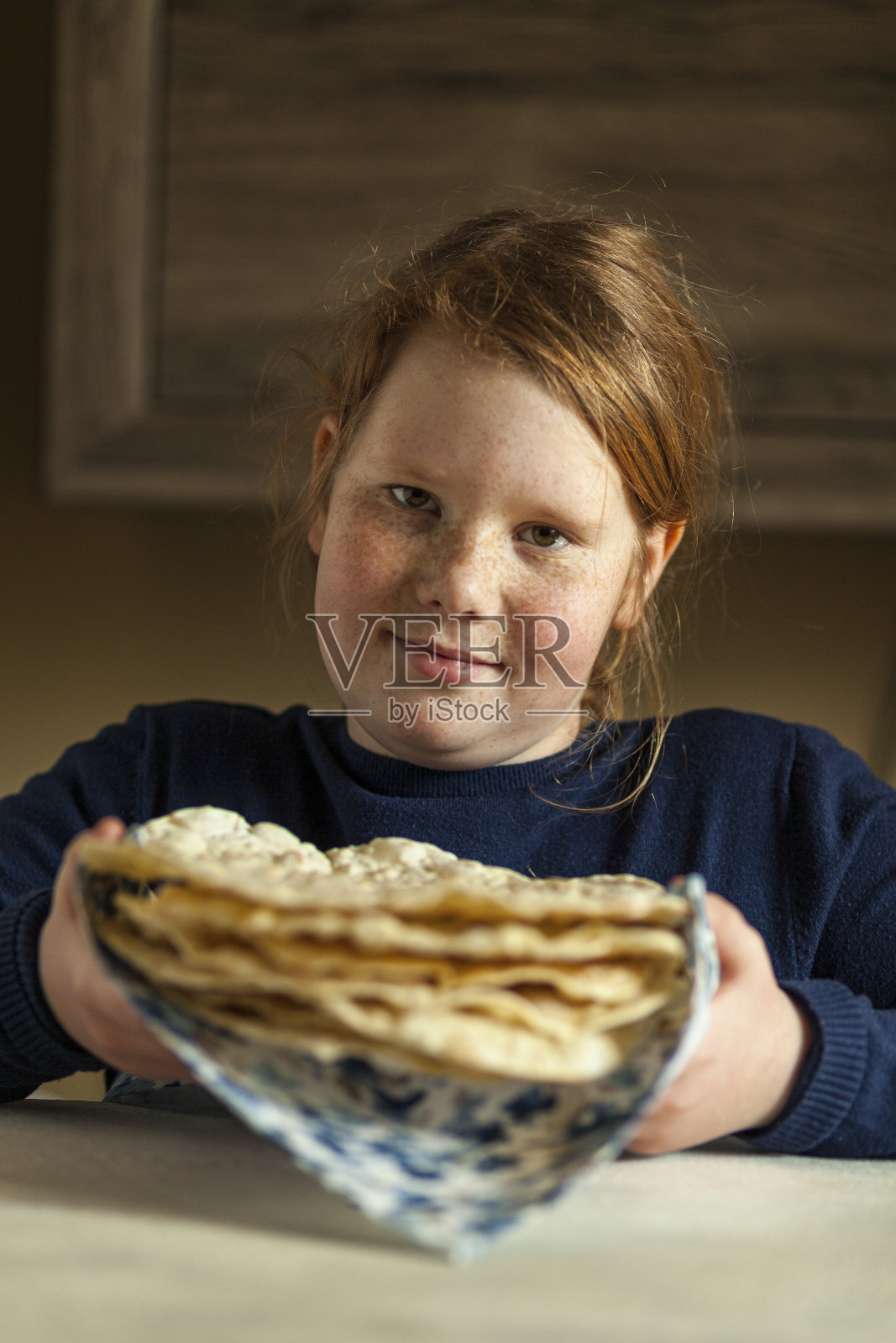 红发的胖女孩，脸上有雀斑，手里拿着自制的皮塔饼，面带微笑。自制的糕点。照片摄影图片