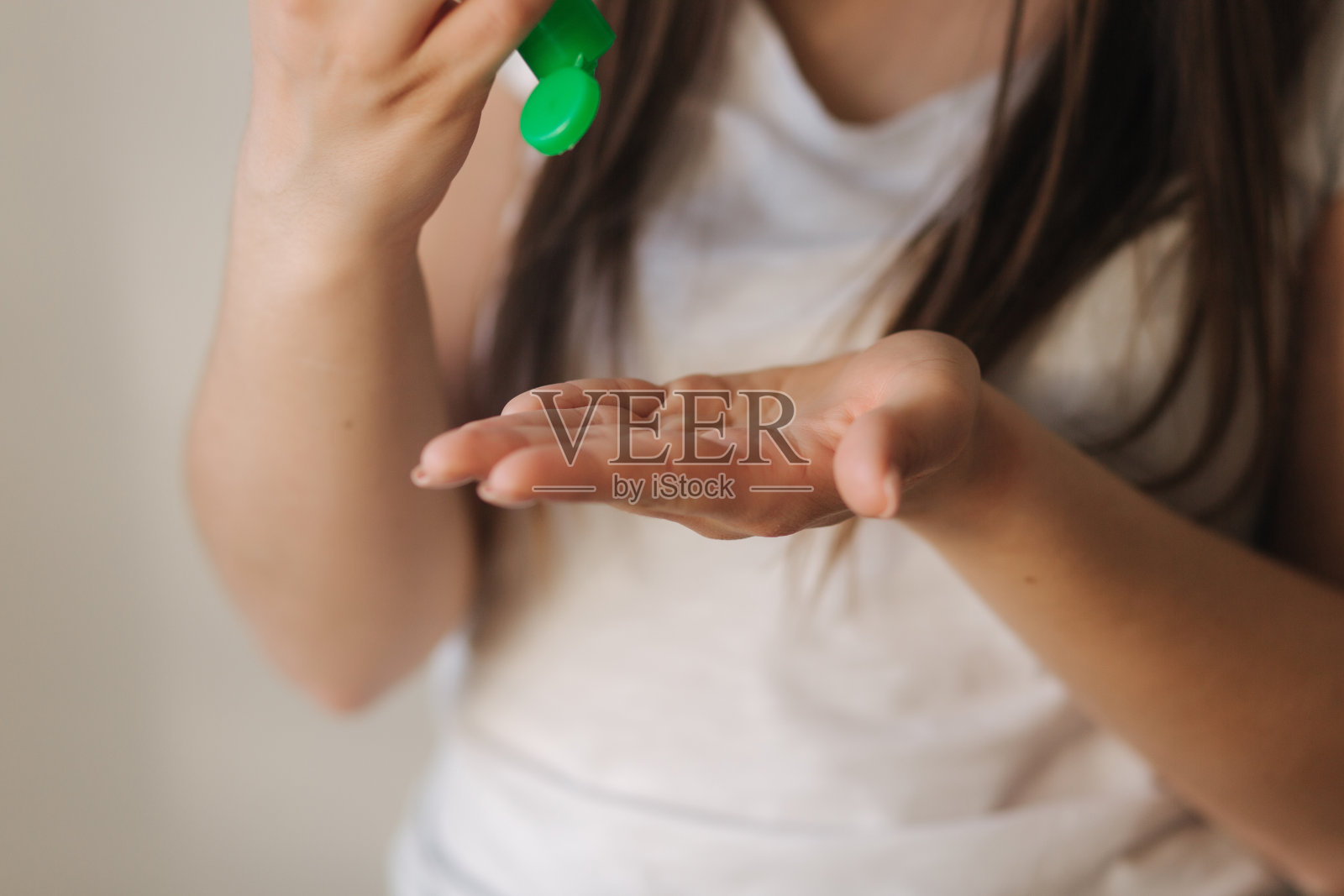 穿着白色t恤和口罩的年轻女子使用消毒液照片摄影图片