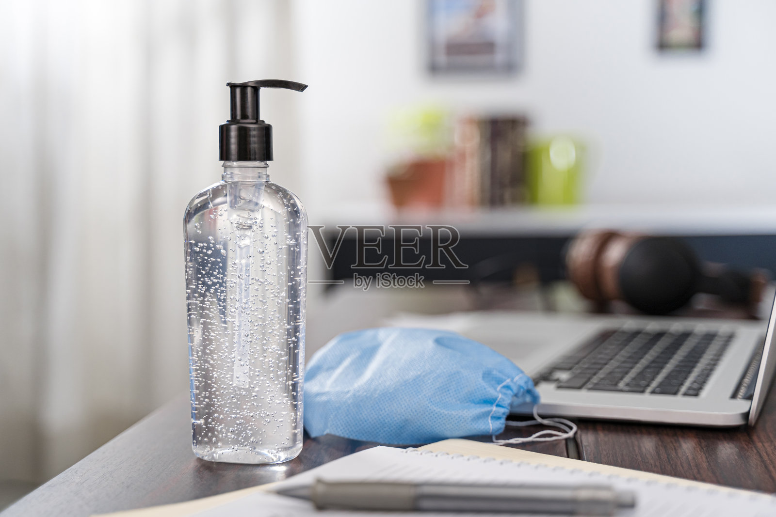 洗手液瓶、酒精凝胶模型、办公桌、家庭办公室、笔记本电脑抗菌冠状病毒检疫隔离文书、大的分配器和口罩、口罩照片摄影图片