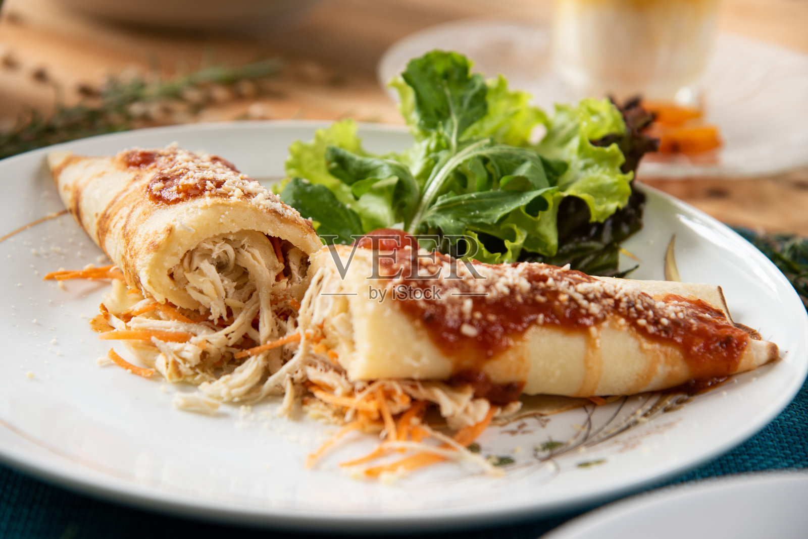 木桌上的白色盘子上放着鸡肉薄饼，背景是沙拉。巴西的煎饼。照片摄影图片