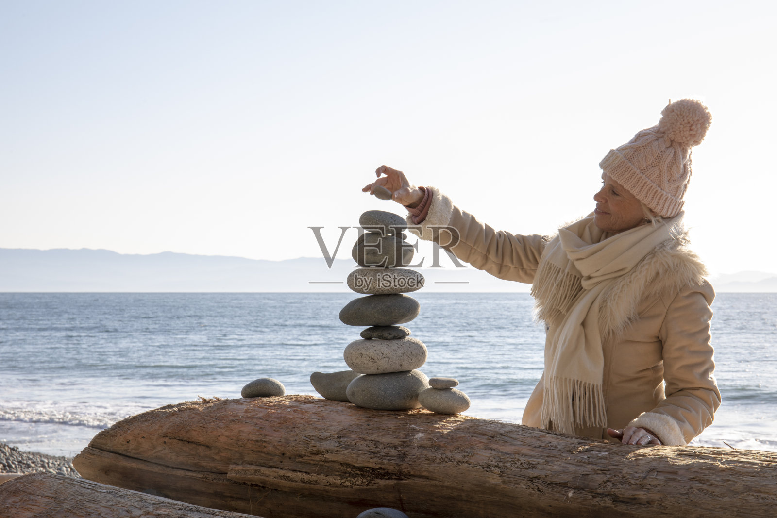 清晨，一名女子在海滩上平衡岩石照片摄影图片