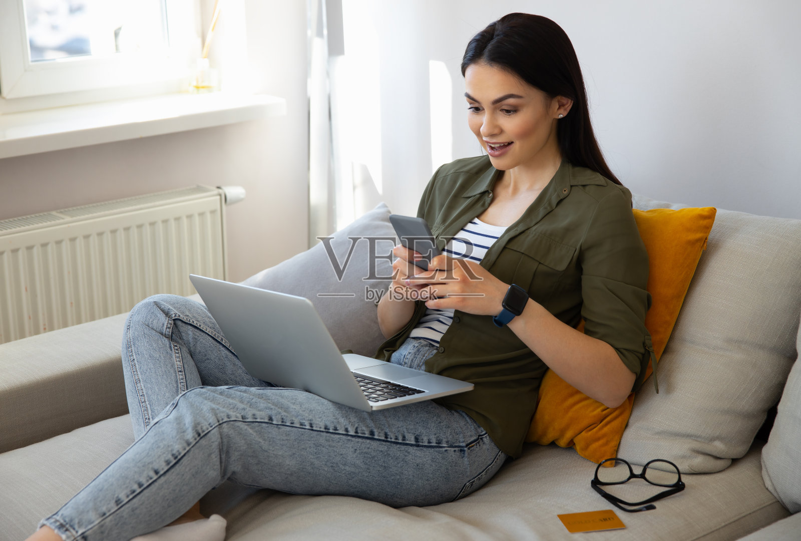 惊奇的漂亮女士在家里使用智能手机照片摄影图片