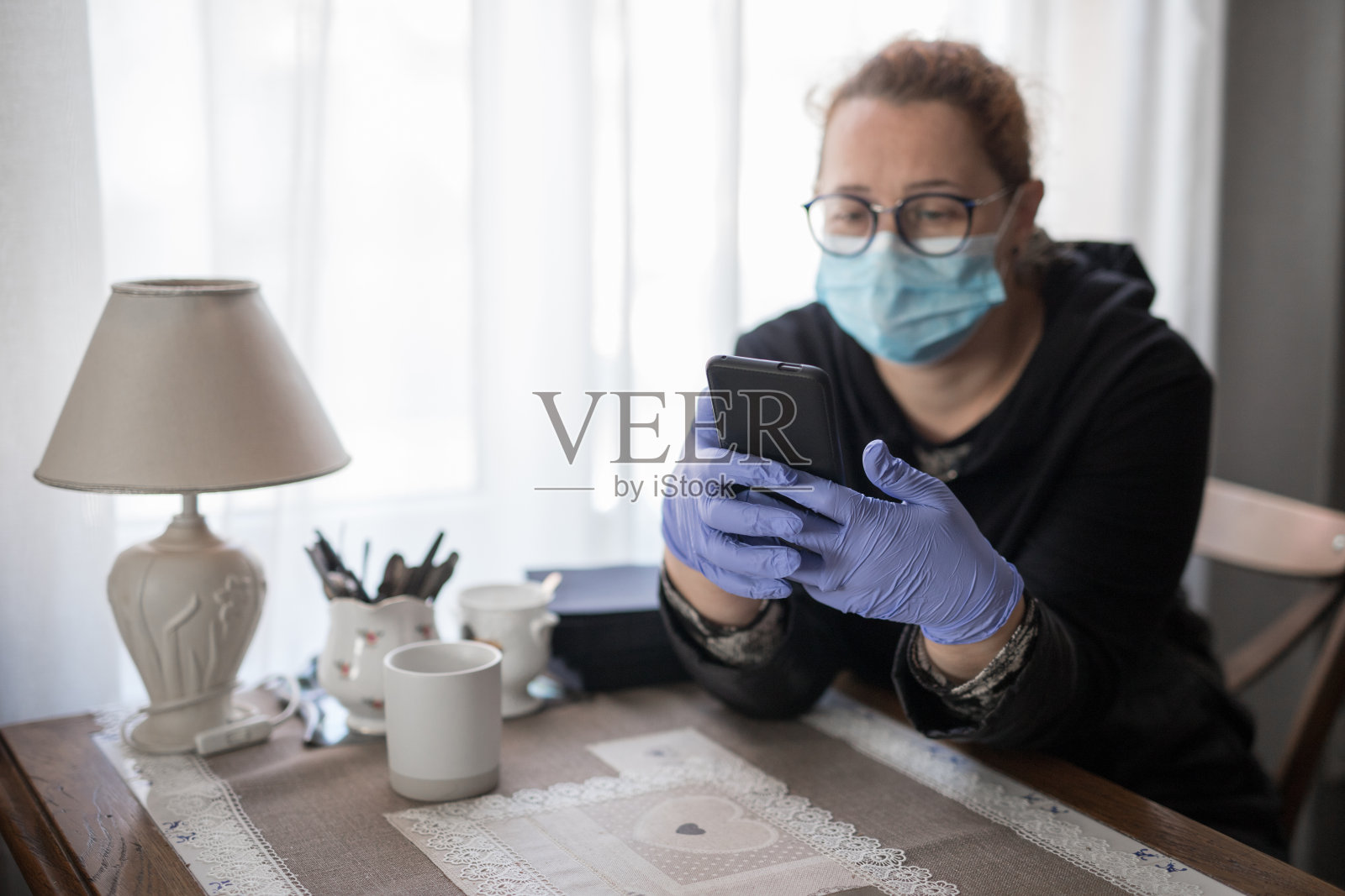 年轻女子与手机防护口罩和手套在隔离在家库存照片照片摄影图片