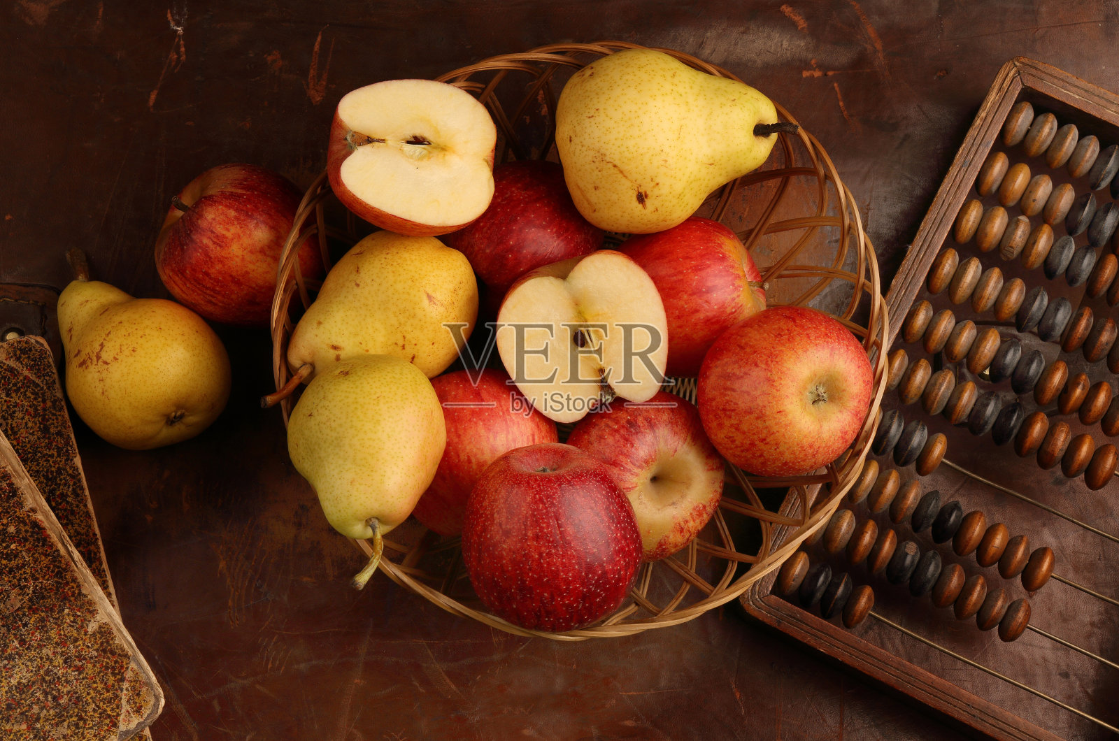 棕色的背景上放着苹果、梨子和老算盘照片摄影图片