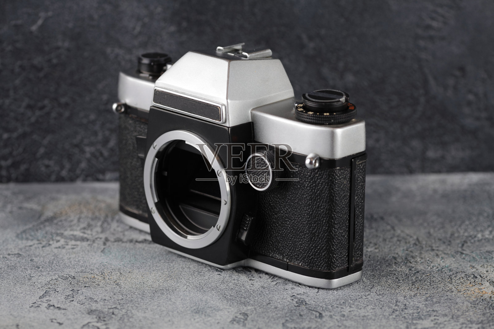 老式的35毫米胶片相机，没有镜头，安装在灰色水泥背景上。照片摄影图片