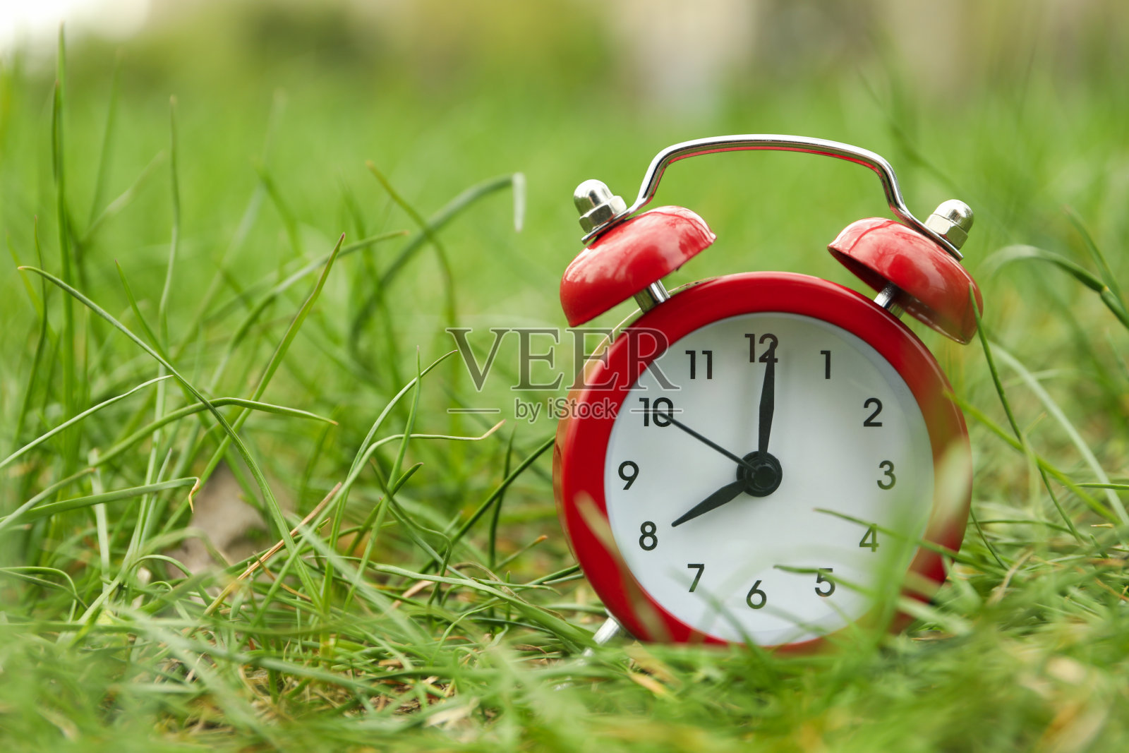 闹钟在绿草的背景。春天照片摄影图片