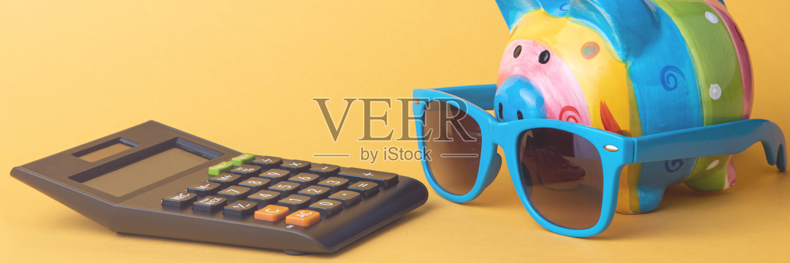 黄色背景上有计算器的储蓄罐，文字空白。金融省钱照片摄影图片