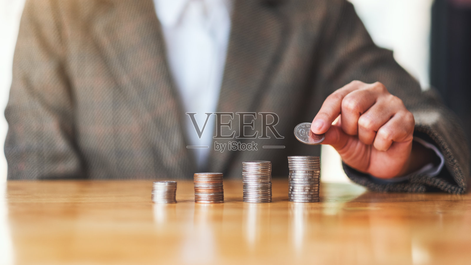 女商人拿着硬币并把它们堆在桌子上照片摄影图片