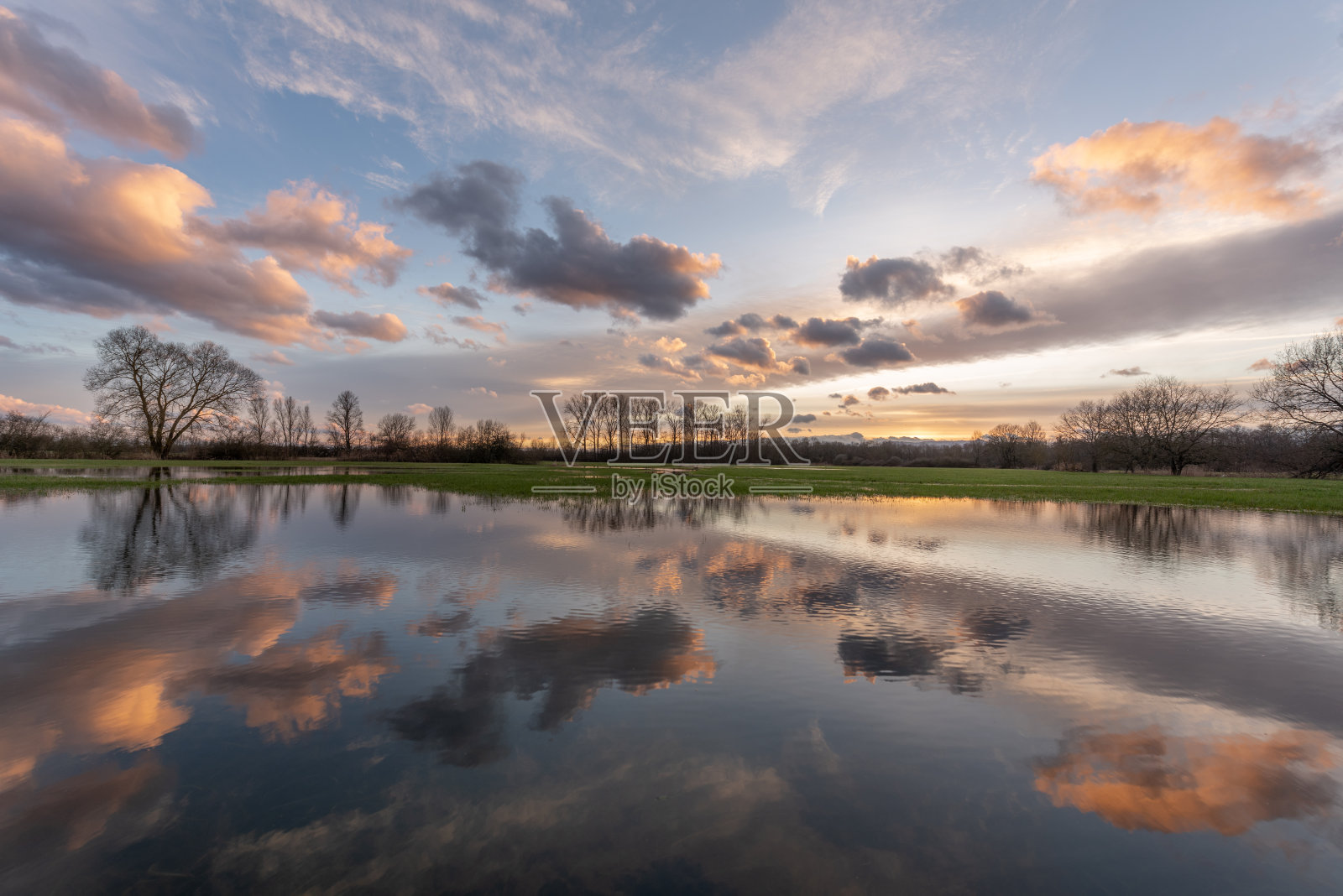 阴天倒映在被淹没的草地上的水面上照片摄影图片