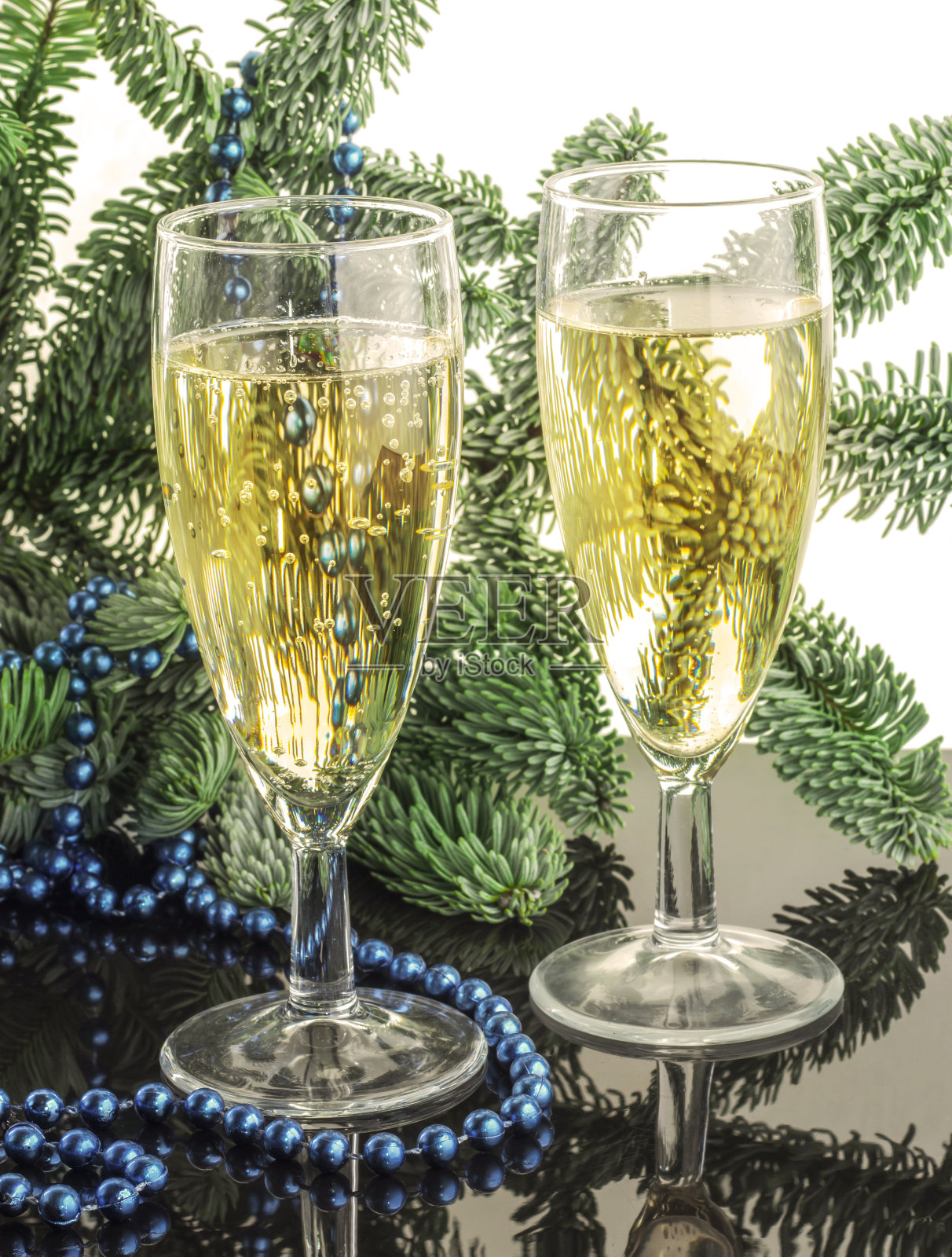 两杯香槟放在圣诞树的背景上照片摄影图片