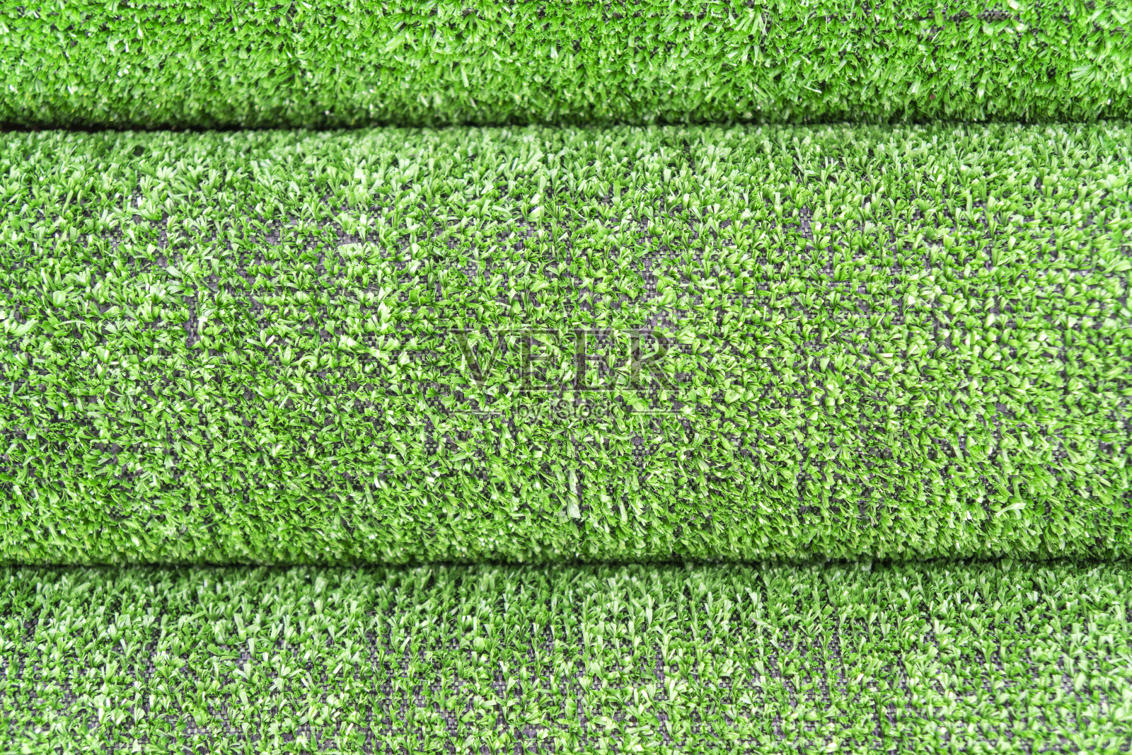 人造草草坪纹理。人造草皮的背景。用人造草绿化。滚动人造草皮铺设背景纹理。一卷合成草层照片摄影图片