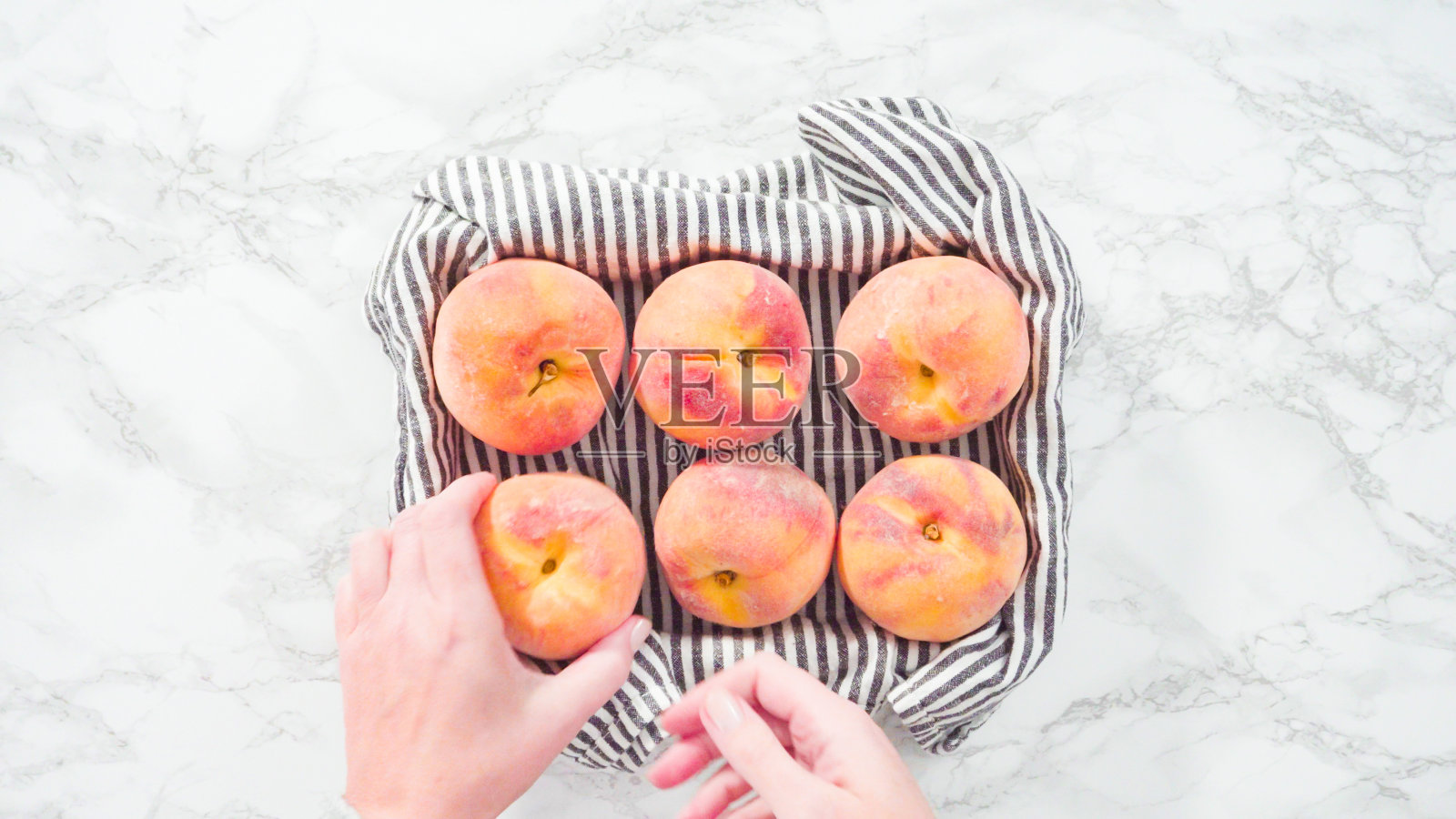 大理石背景上的篮子里的有机桃子。照片摄影图片