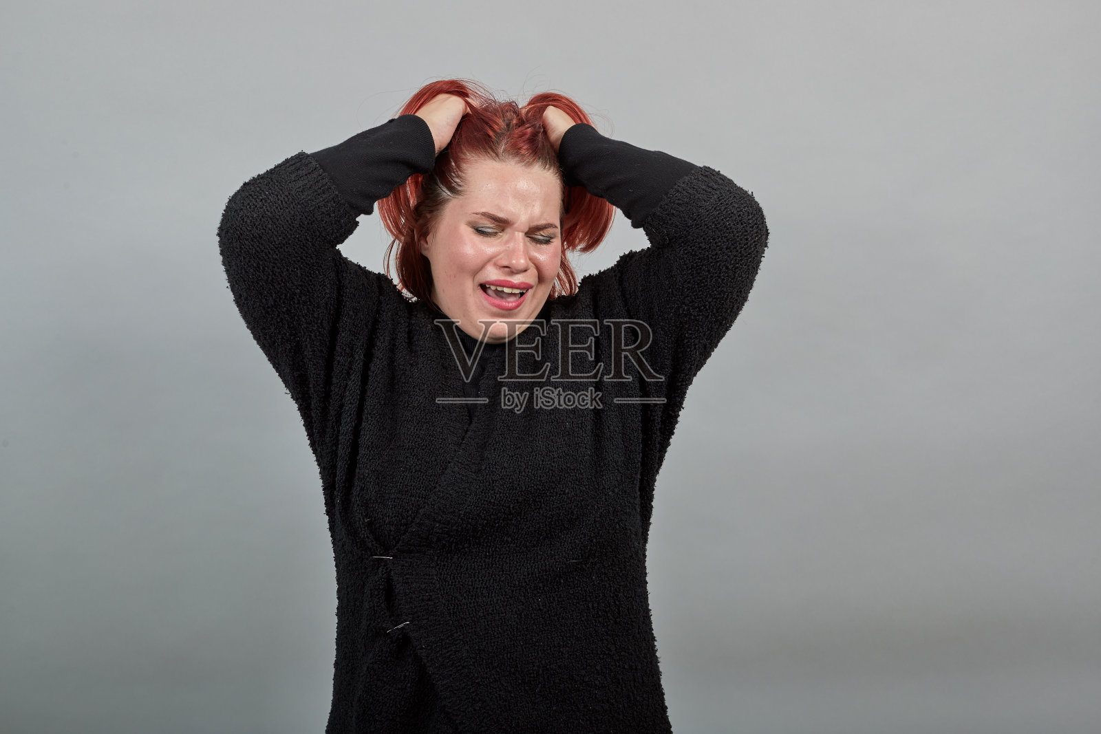 穿着黑色毛衣的年轻胖女人哭泣，双手抱头，感到沮丧照片摄影图片