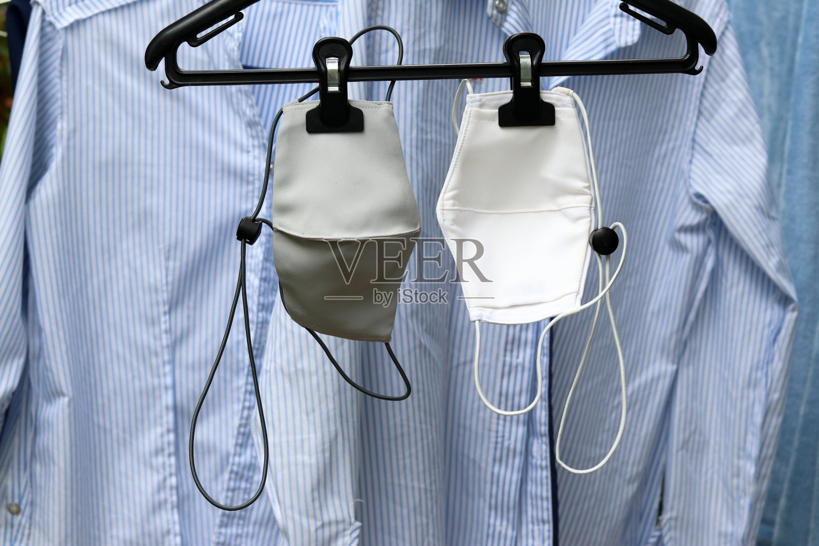 可重复使用的布口罩，可调节耳圈和颈带挂在衣架上。照片摄影图片