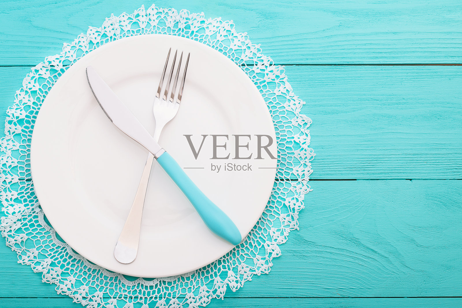 蓝色木质背景的蕾丝桌布上的婚礼餐具。俯视图和复制空间。有选择性的重点照片摄影图片