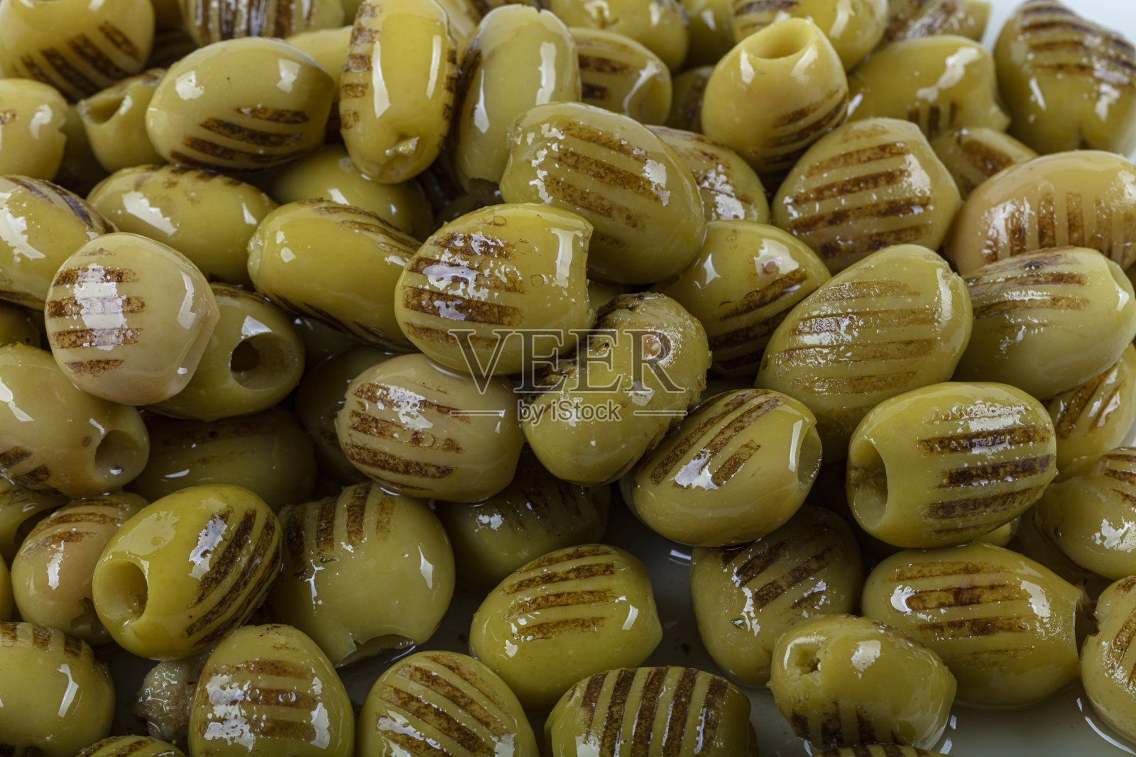 在白色背景的购物车里，烤绿橄榄。照片摄影图片