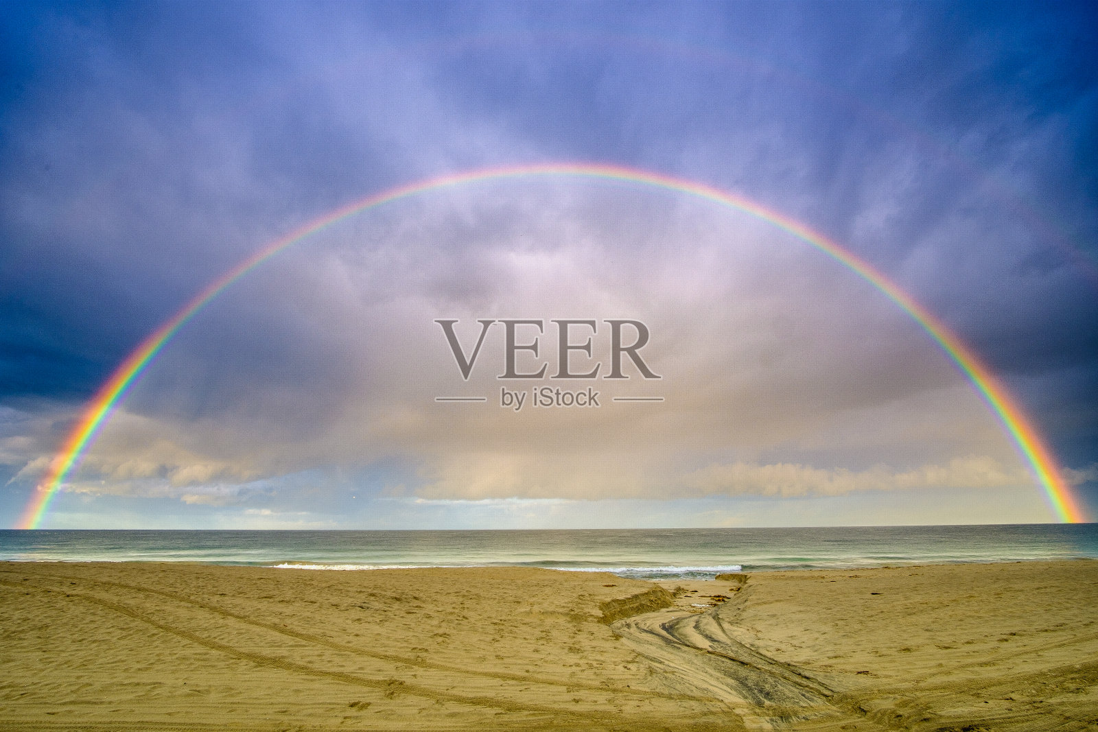 在海滩上，海面上出现了一道强烈的彩虹照片摄影图片