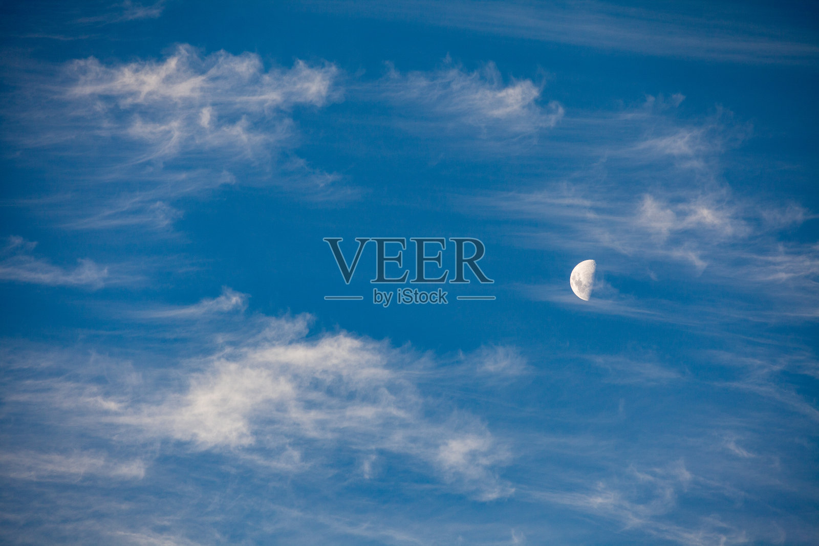 月亮的第一个季度在蓝天与风扫白云照片摄影图片