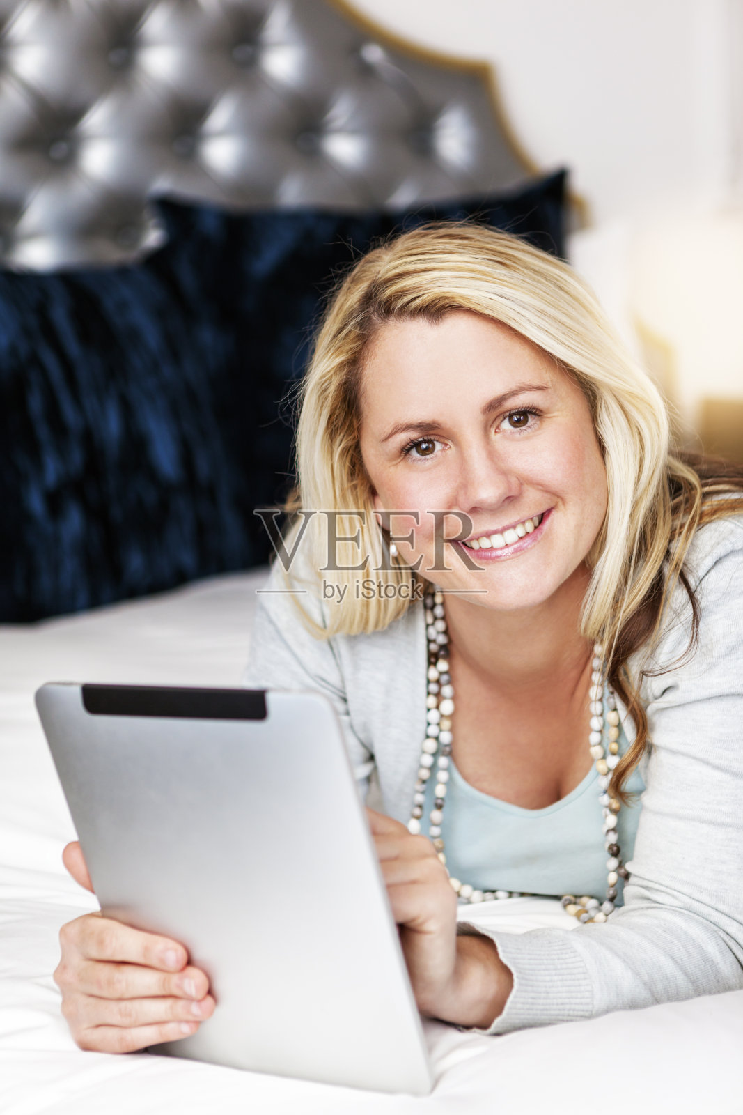 一名女子躺在床上用着平板电脑微笑照片摄影图片
