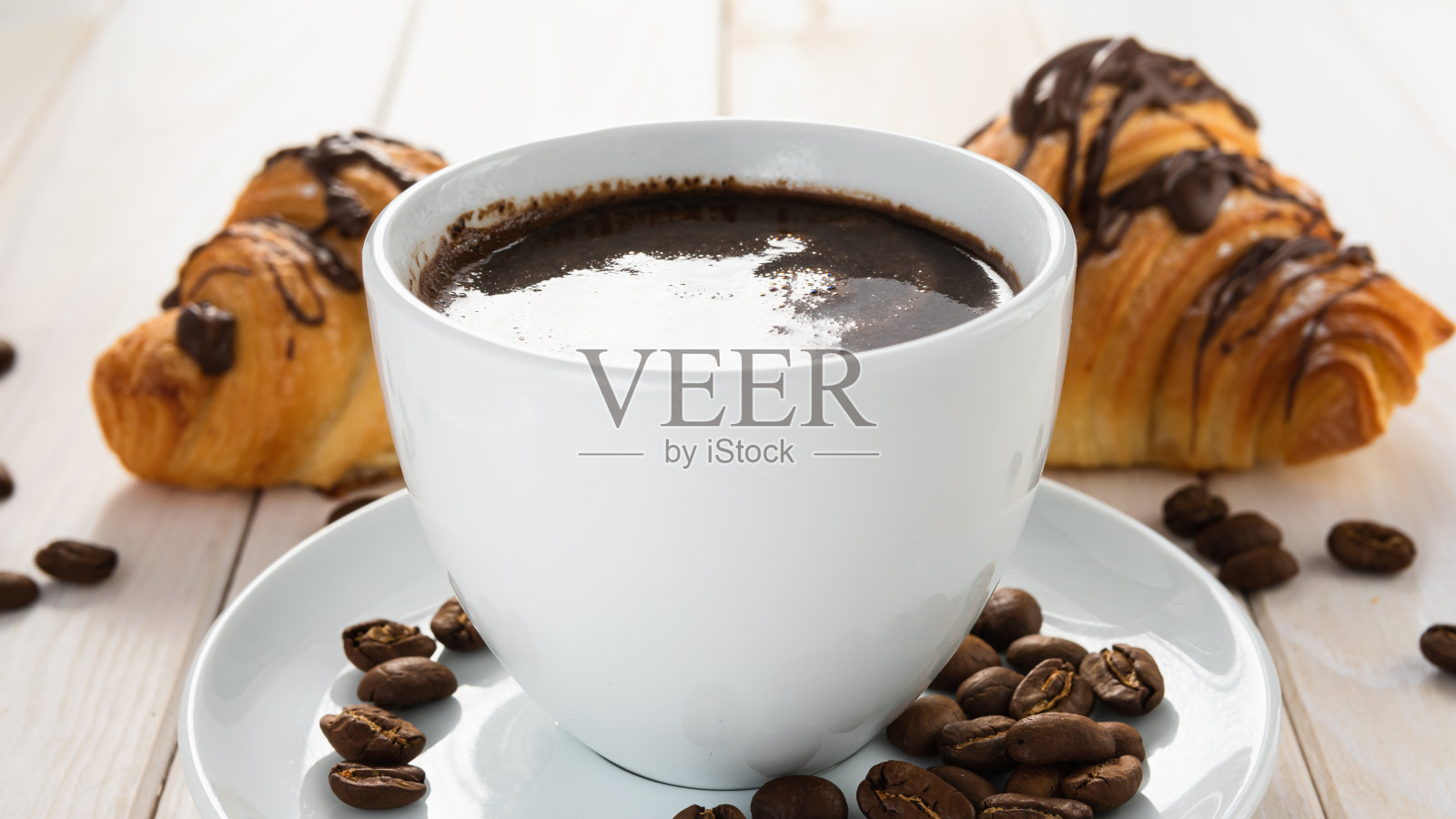 白色的木桌上放着两块羊角面包和一杯咖啡照片摄影图片