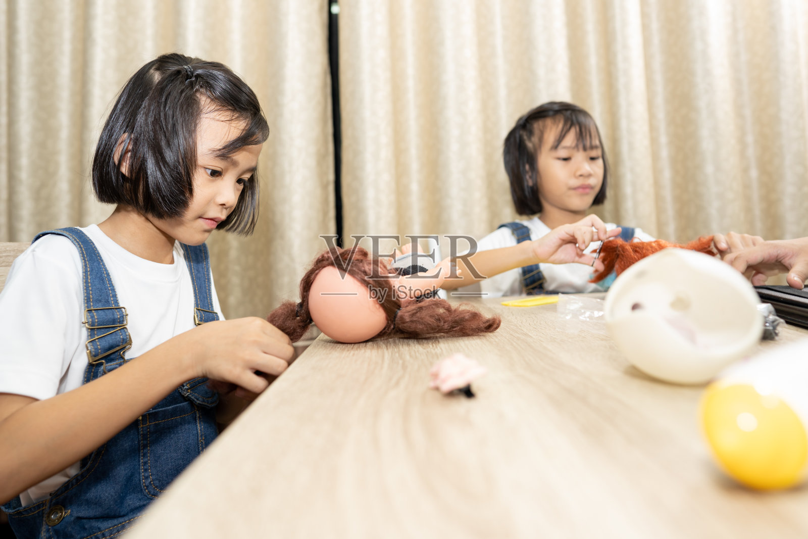 孩子们玩而呆在家里，孩子们在家里的桌子上玩娃娃照片摄影图片