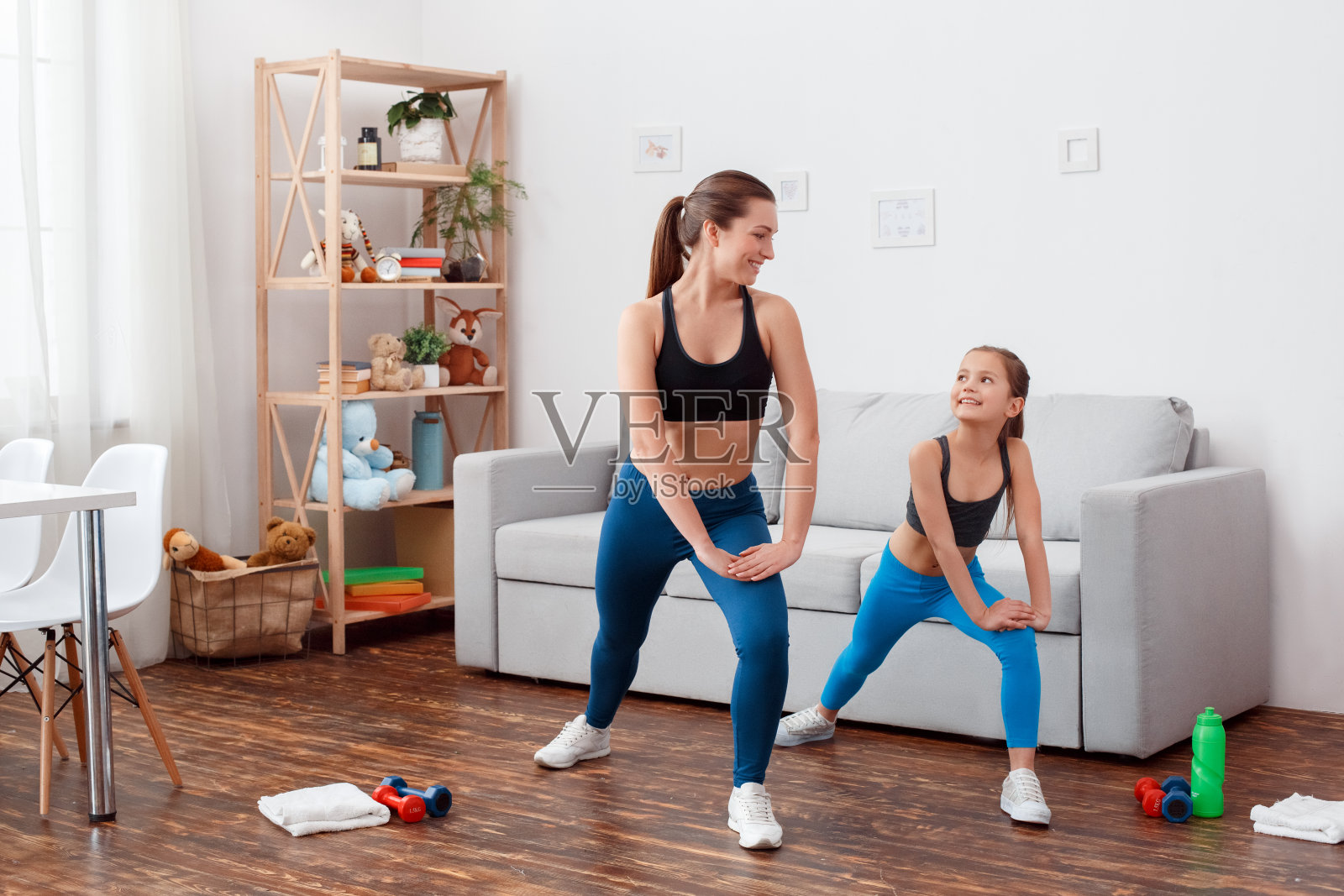 水平工作室概念在家白光背景与运动设备。教练女女女孩瑜伽教练训练小美小女孩在室内做伸展运动。照片摄影图片