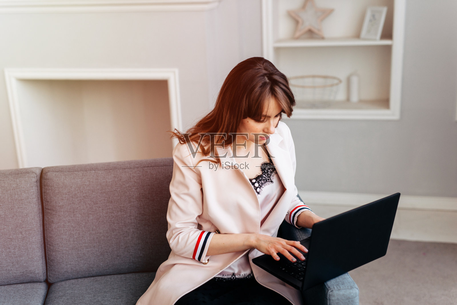 坐在沙发上用笔记本电脑办公的女人照片摄影图片