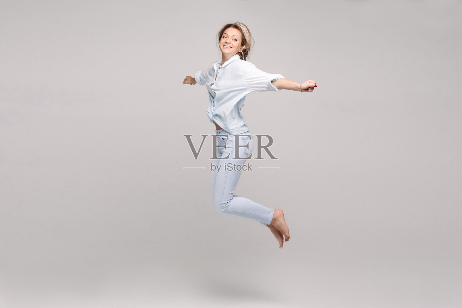 观之积极而快乐的漂亮金发女郎，穿着优雅的套装跳了起来。照片摄影图片